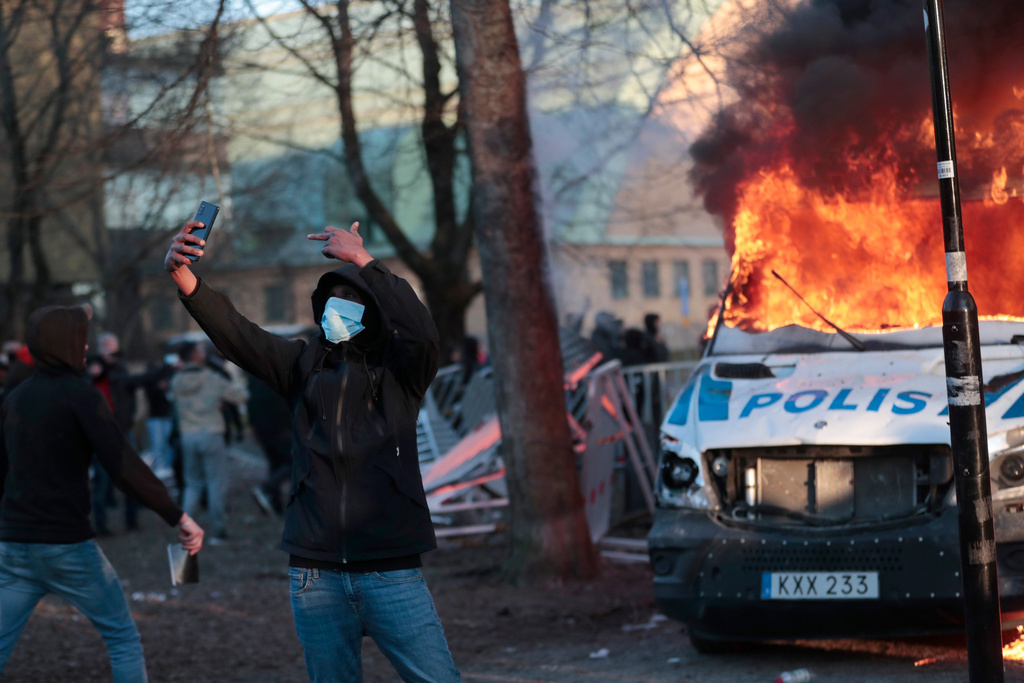 En demonstrant filmar sig själv framför en av de tre polisbussar som sattes i brand vid upploppen i Örebro. Kicki Nilsson/TT